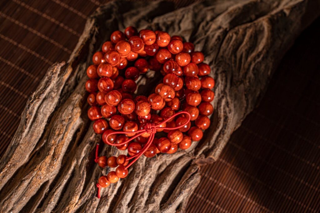 pexels-photo-31005907 A close-up of a red wooden bead bracelet on textured wood background.